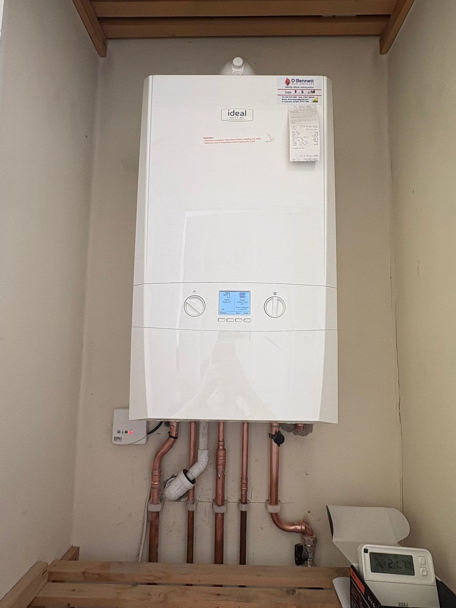Ideal Heating combi boiler with copper pipework and a wired thermostat in a domestic cupboard